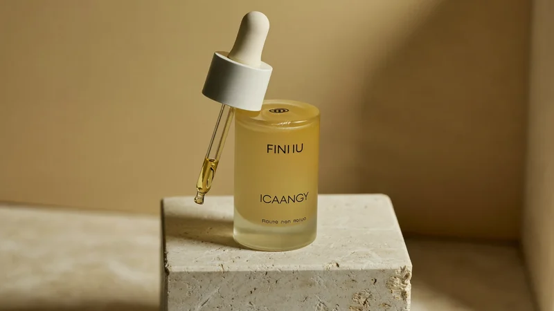 Mattiertes Tropfenfläschchen mit goldenem Serum auf einem Travertinblock, illustrative Darstellung.